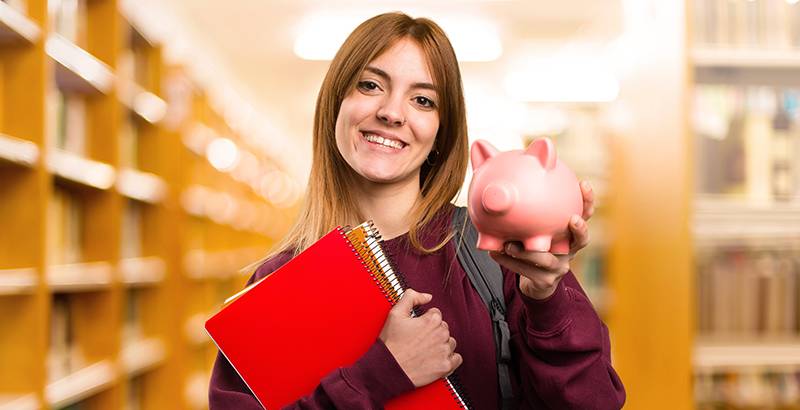 Girl holding book and piggy bank