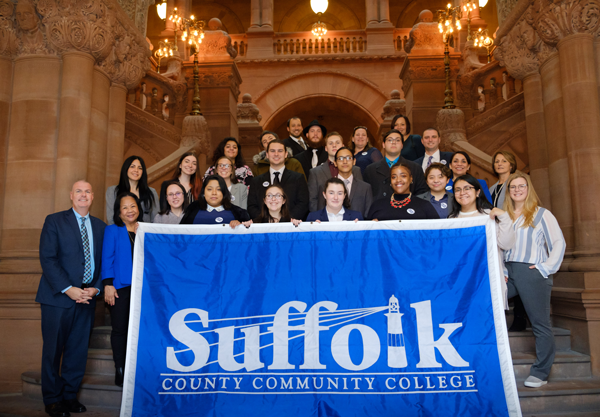 students pose in the New York State Capitol with a Suffolk banner